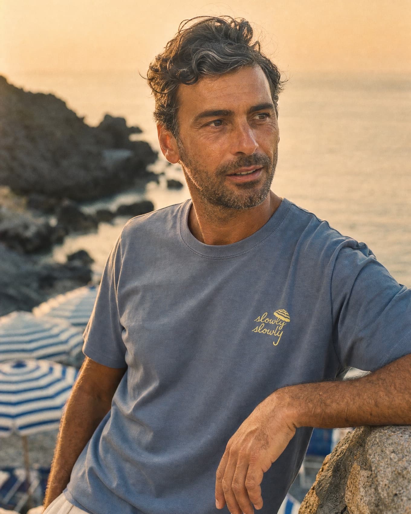 Amalfi Tee worn on the rocks above the cove at golden hour, slowly slowly chest mark visible